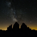 Drei Zinnen (Tre Cimi di Lavaredo), icoon van de Dolomieten. Licht vanaf de Po-vlakte zorgt voor een gele gloed, maar verder zijn de sterren en de melkweg zeer helder. Op de Westliche Zinne (rechts) is een lichtje te zien: geen ster, maar een touwgroep in de fameuze noordwand.